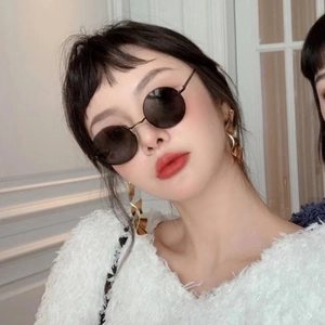 Chic model wearing vintage round sunglasses with dark lenses and gold earrings