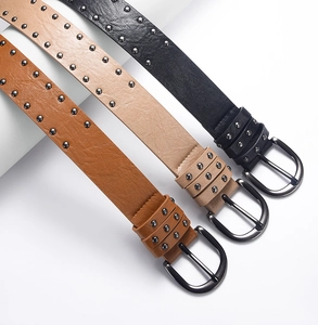 Detail view of double-row rivet leather belts in brown, beige, and black with D-ring buckles