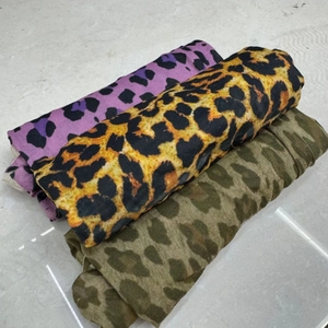 Three rolls of leopard print patterned leggings in purple, classic yellow, and olive green