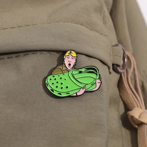 Kreative Emaille-Anstecknadel mit Cartoon-Junge und grünem Slipper an einem Rucksack