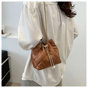 Detail view of brown quilted bucket bag with gold chain strap and pearl drawstring