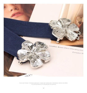Detailed close-up of dark blue woven elastic belt with silver floral metal buckle clasp