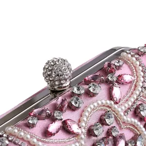 Close-up of pink satin evening clutch featuring intricate pearl and rhinestone floral beadwork