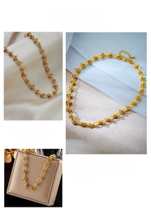 Detailed close-up of golden interlocking link chain necklace with lobster clasp and extender