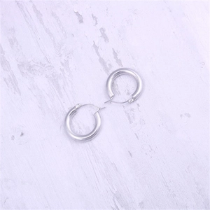 Detailed view of polished silver round hoop earrings in stainless steel on a desk