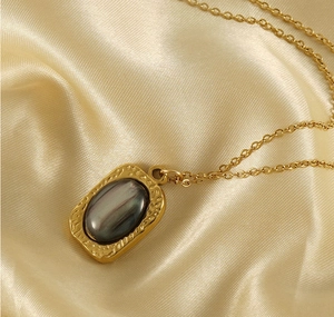 Macro detail of rectangle gold tiger eye pendant on champagne silk fabric background