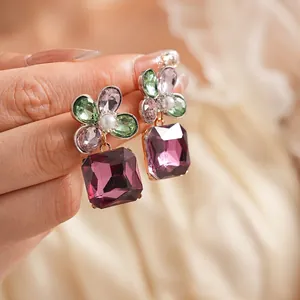 Vintage floral square earrings with purple crystals and pearls held in hand