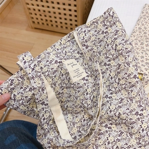 Detailed close-up of a floral canvas tote bag with a minimalist woven label and wide straps