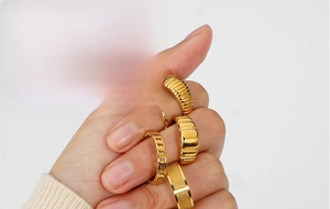 Close-up of five-piece gold ring set featuring minimalist chain and textured band designs
