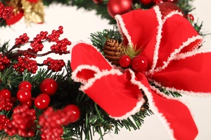 Close-up of Christmas wreath featuring red velvet bow, faux berries and pine cones