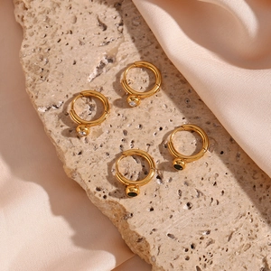 Detail of 18K gold plated earrings with zircon and emerald green gemstone pendants