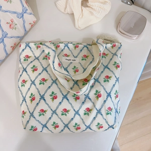 Detail of floral canvas tote bag with blue ribbon patterns and rose print motifs