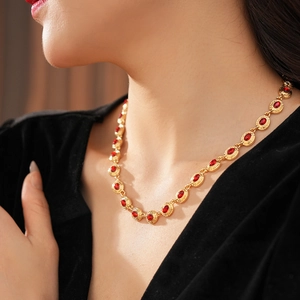 Détail d'un collier vintage doré avec cristaux ovales rouges sur une tenue en velours noir