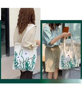 Detail of chamomile print canvas tote bag showing model carrying and text embroidery
