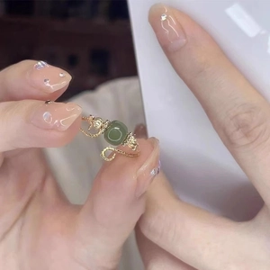 Retro style open ring featuring a twisted gold band and a round green gemstone