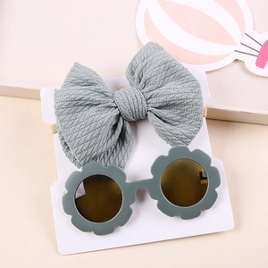Baby gift set with a grey waffle bow headband and green flower sunglasses on a white card