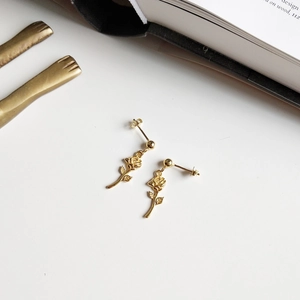 Elegant gold rose flower dangle earrings in 925 sterling silver on a minimalist background