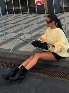 Detail of pale yellow cable-knit oversized sweater with drop shoulders and ribbed texture