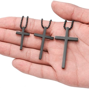 Detailed size comparison of three black stainless steel cross pendants on a hand