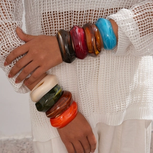 Close-up of colorful chunky acrylic geometric bangles worn by a model in detail