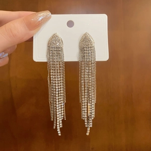 Detailed view of silver-toned long tassel earrings featuring sparkling rhinestones and metallic fringes