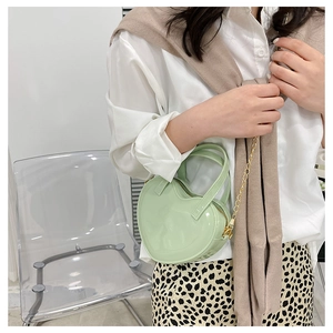 Detailed view of mint green heart-shaped mini bag with glossy finish and gold chain strap