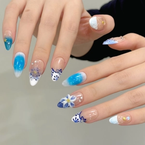 Blue and white stiletto press-on nails with 3D floral accents and ocean style gradient