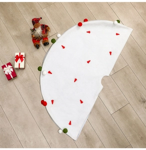 Vue détaillée du tapis de sapin de Noël en peluche blanche avec motifs rouges et pompons