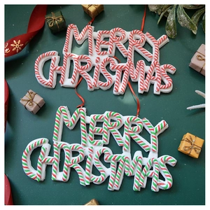 Close-up of striped Merry Christmas clay ornaments with glitter and red hanging ribbons