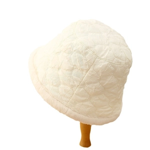 Quilted white winter bucket hat with plush faux fur trim on a wooden display stand