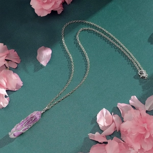 Macro detail of purple crystal pendant with silver tree of life wire wrapping