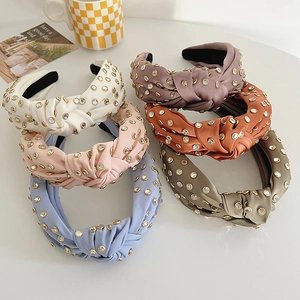 Detailed view of six colorful satin knotted headbands with rhinestones on a white surface