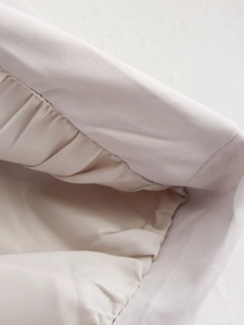 Macro view of cream woven twill fabric showing detailed ruching and texture structure