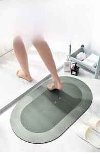 Detail view of oval absorbent bath mat with HOME text on a marble bathroom floor