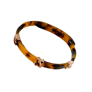 Maillard leopard tortoiseshell crossover bangle with rose gold knot accents on white background