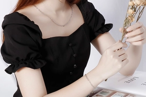 Close-up of a minimalist silver chain necklace and bracelet set on a female model