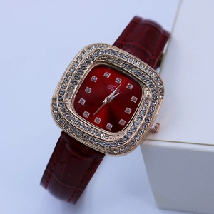 Détails d'une montre carrée en or rose avec diamants étincelants et bracelet en cuir rouge