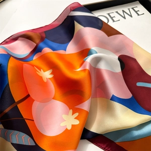 Close-up of vibrant floral print silk scarf showing smooth texture and draped fabric