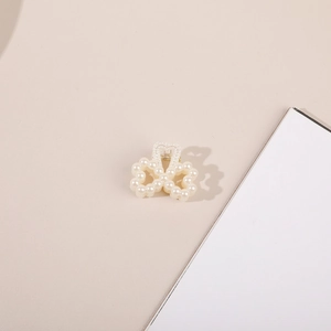 Close-up of elegant bow-shaped pearl mini hair claw clip with cream white beads