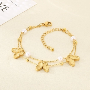 Close-up of double-layer stainless steel bracelet with gold butterfly charms and white pearls