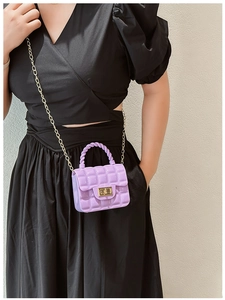 Close-up of a purple quilted jelly bag with a gold metal lock worn by a model
