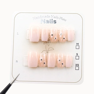 Pink gradient press-on nails with handmade white flower design and sparkling rhinestones