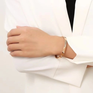 Detailed macro view of gold stainless steel clover bangle with cubic zirconia on a wrist