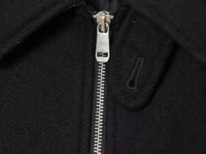 Detail of silver metal zipper on black wool-textured fabric for stylish street jackets