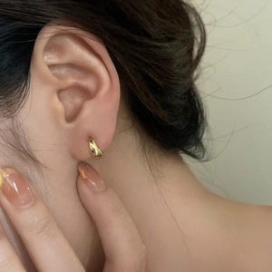 Minimalist gold hoop earrings with high polish finish shown as a close-up on ear