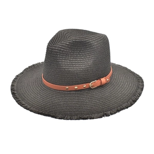 Detail of dark straw sun hat with fringe brim and brown leather strap with gold studs