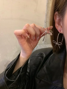 Detailed view of silver bow-shaped hoop earrings worn by a model in a modern urban style