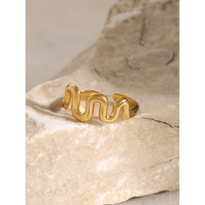 Nahaufnahme eines goldenen gewellten Edelstahlrings auf einer natürlichen Steinfläche