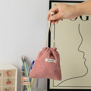 Detail view of pink corduroy drawstring storage bag with soft texture and white fabric label