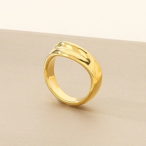 Macro view showing the glossy gold wave ring texture on a brushed metallic stand